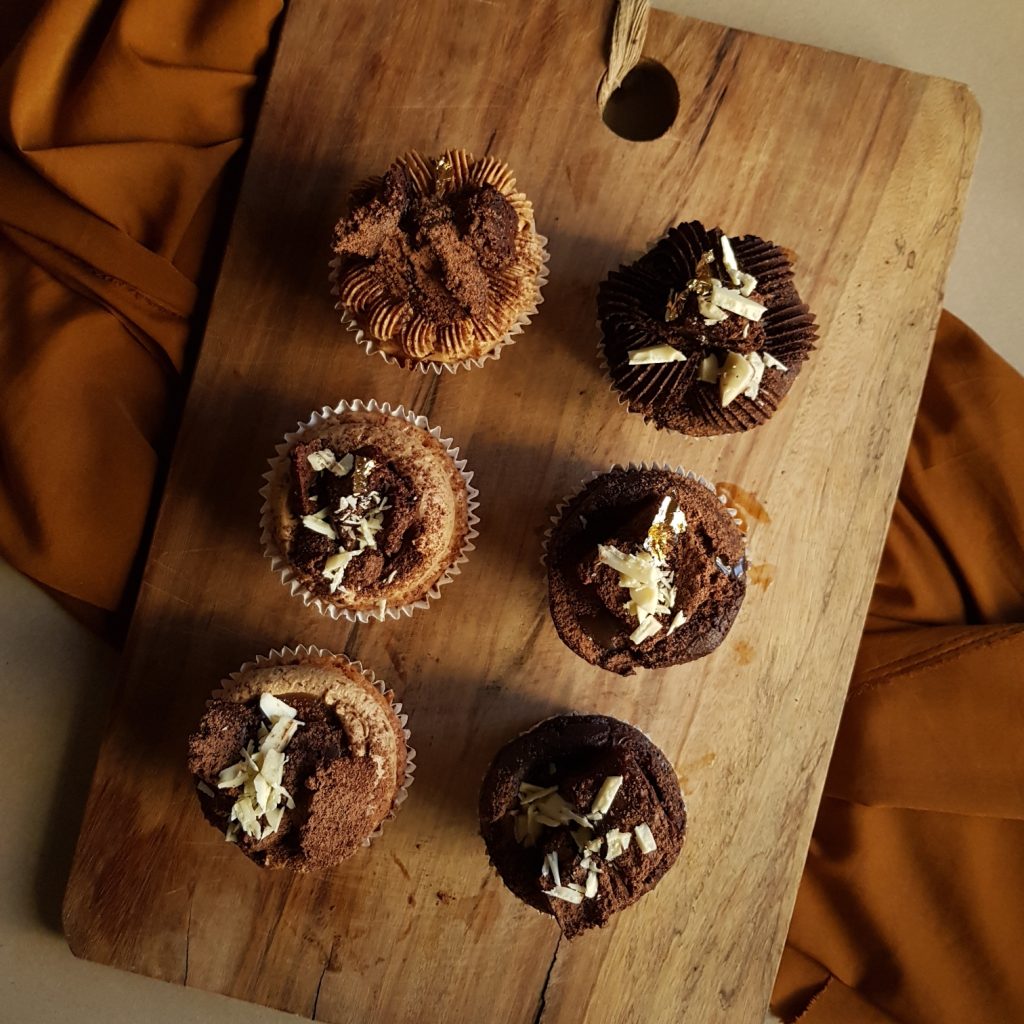 Double chocolate cupcakes, white chocolate mud cupcakes with double chocolate buttercream, coffee buttercream and double chocolate brownie, caramel sauce, cocoa powder, peanuts, crushed white chocolate and gold leaf 